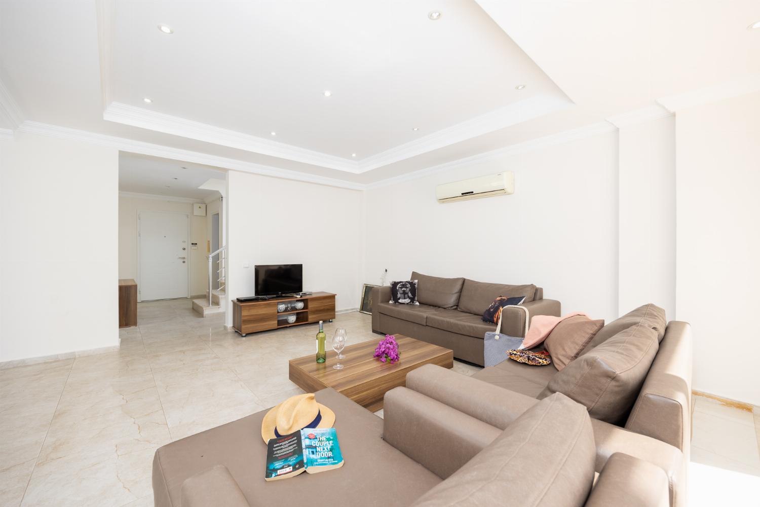 Open-plan living room with sofas, dining area, kitchen, A/C, WiFi internet, and satellite TV