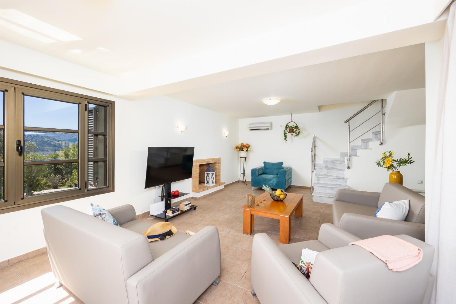 Open-plan living room with sofa, dining area, kitchen, ornamental fireplace, A/C, WiFi internet, and satellite TV