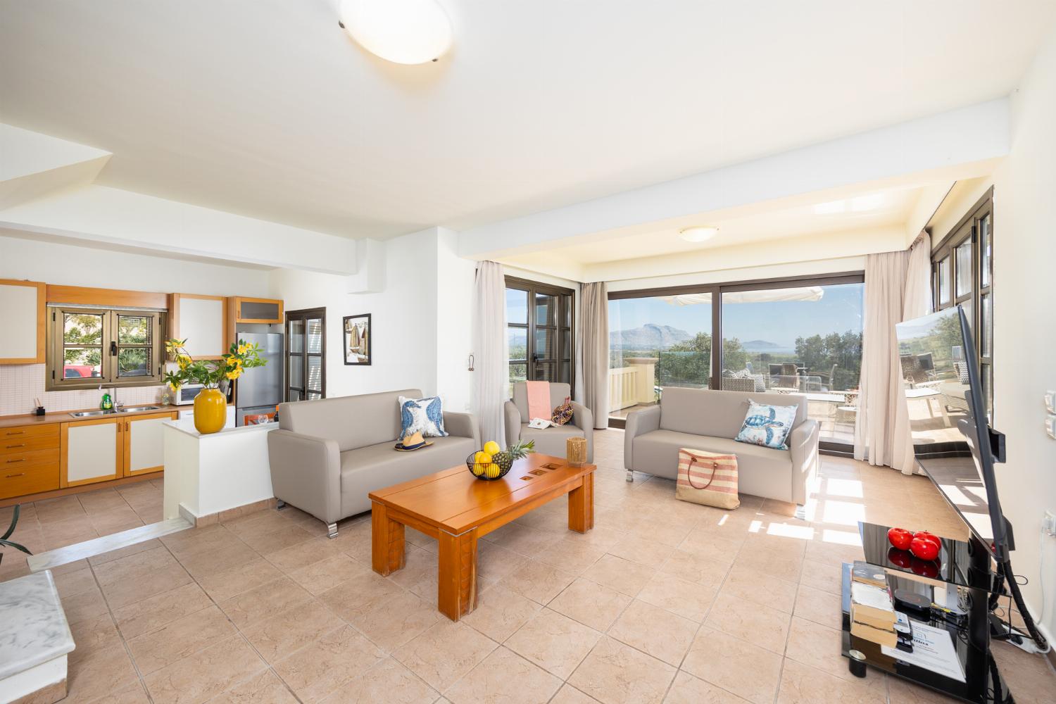 Open-plan living room with sofa, dining area, kitchen, ornamental fireplace, A/C, WiFi internet, and satellite TV
