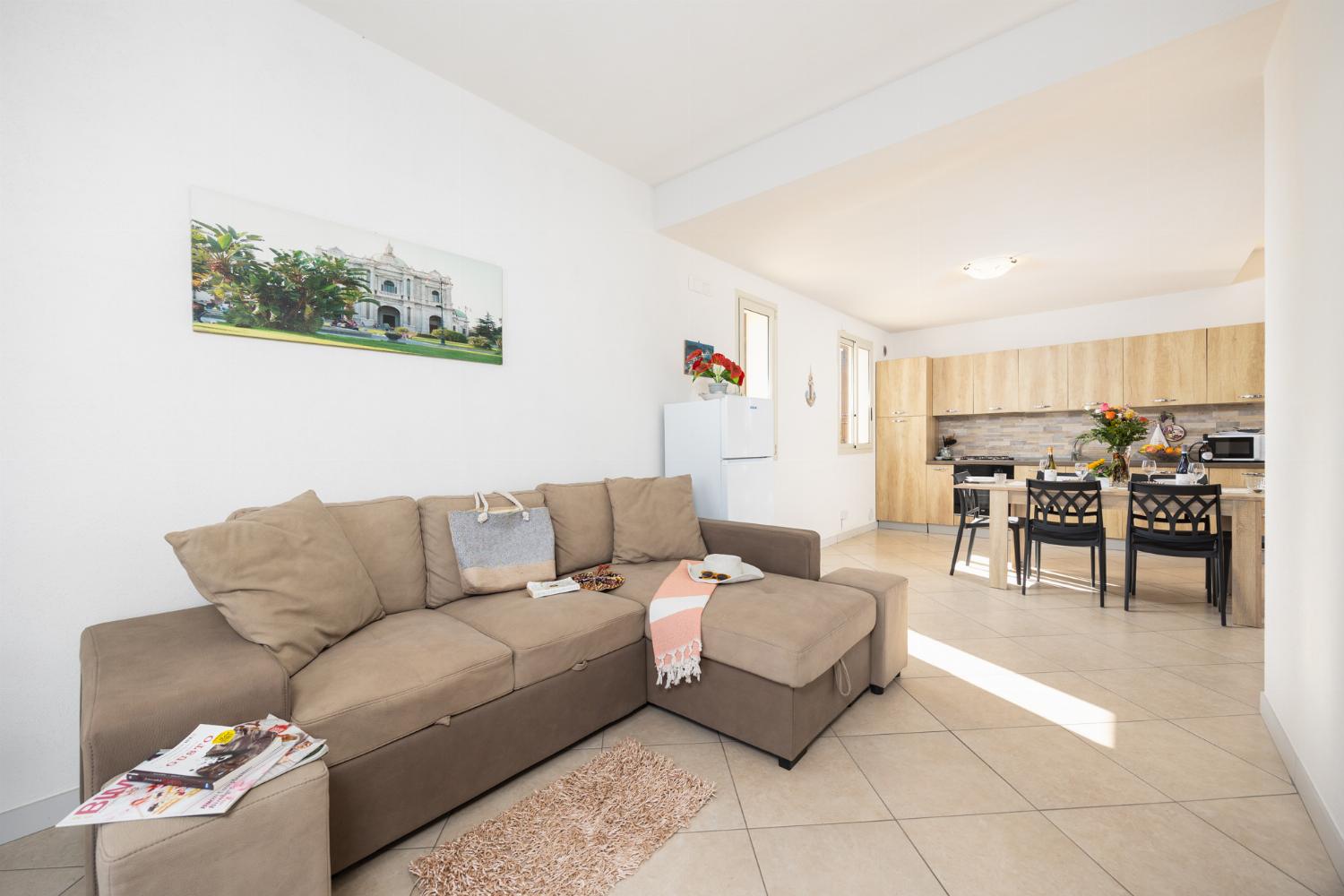 Open-plan living room with sofa, dining area, kitchen, A/C, WiFi internet, and satellite TV