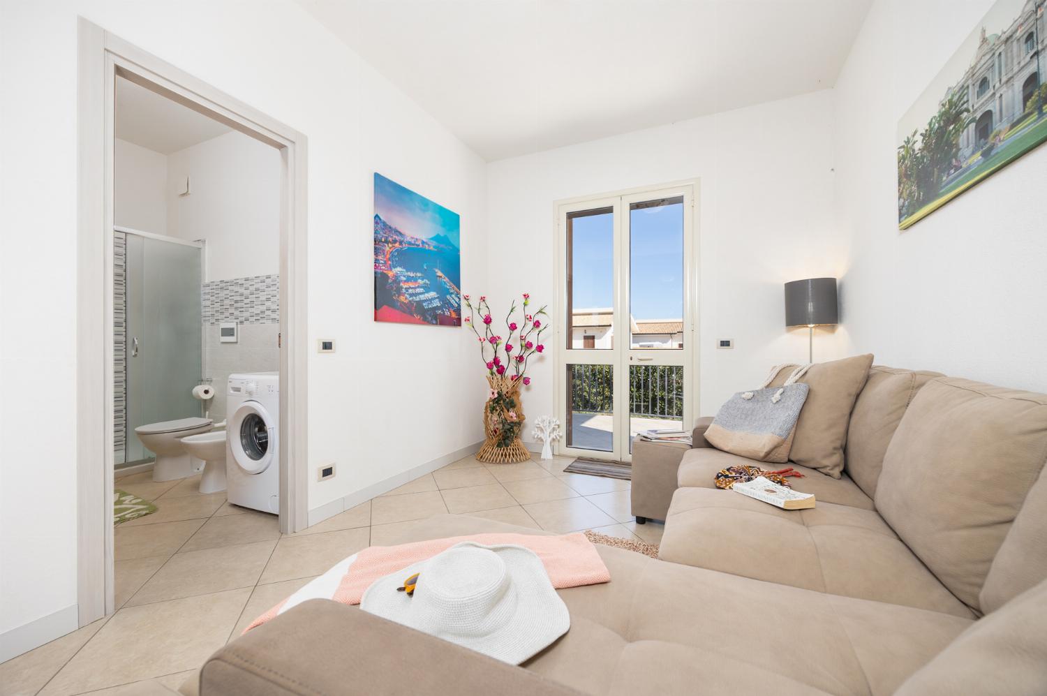 Open-plan living room with sofa, dining area, kitchen, A/C, WiFi internet, and satellite TV