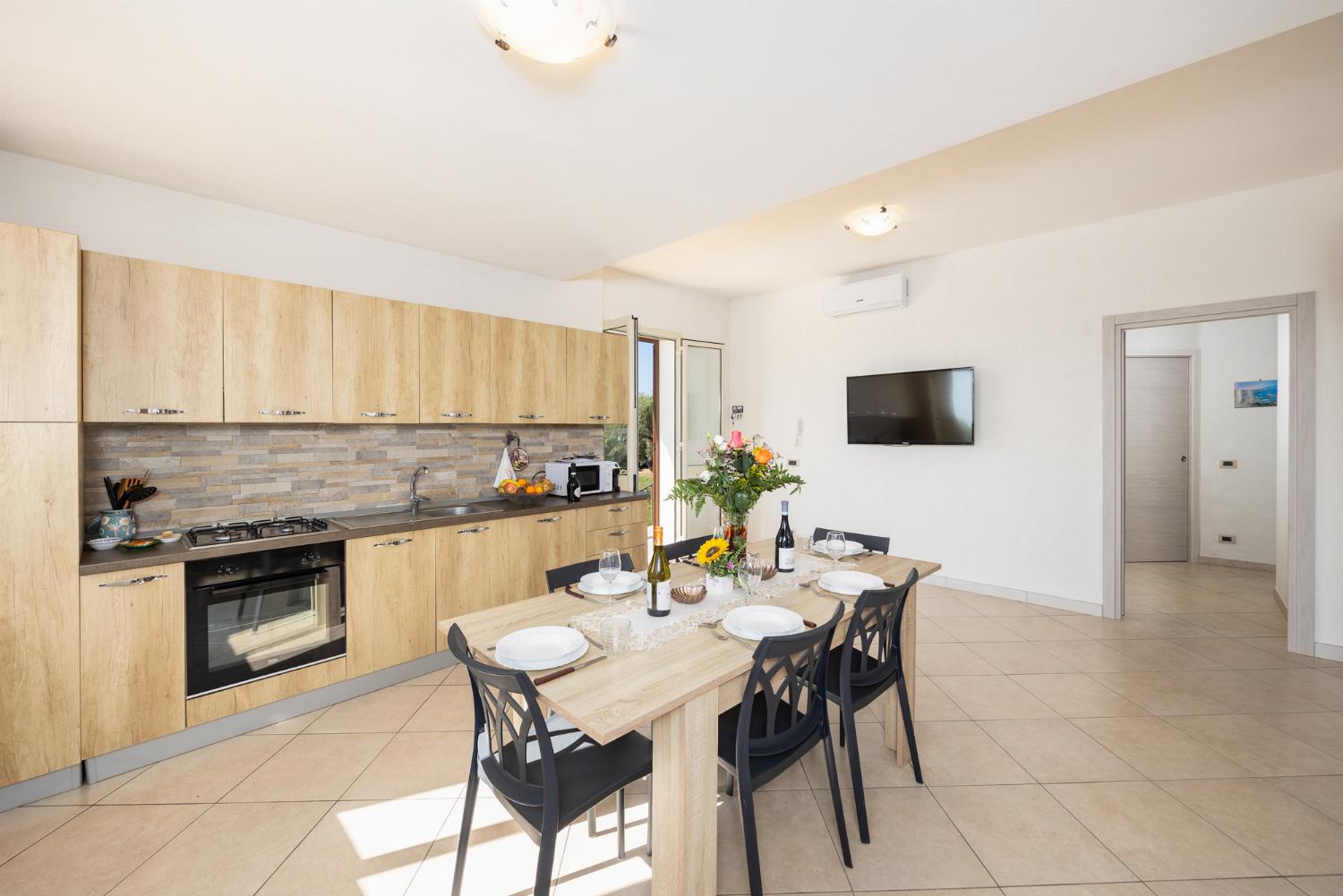 Open-plan living room with sofa, dining area, kitchen, A/C, WiFi internet, and satellite TV