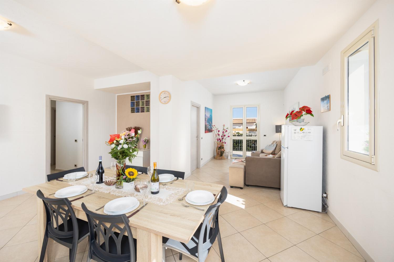 Open-plan living room with sofa, dining area, kitchen, A/C, WiFi internet, and satellite TV