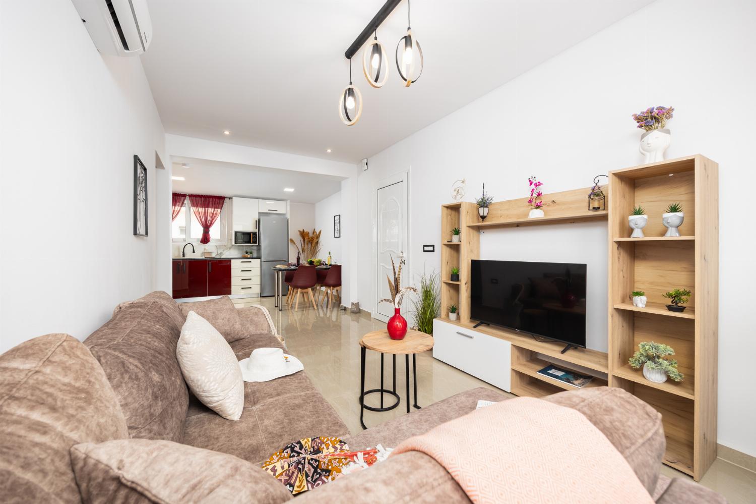 Open-plan living room with sofa, dining area, kitchen, A/C, WiFi internet, and satellite TV