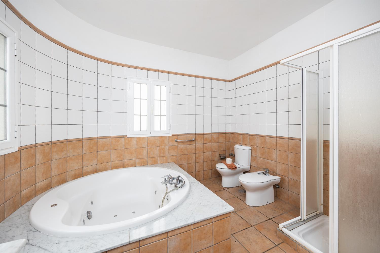 En suite bathroom with jacuzzi and shower