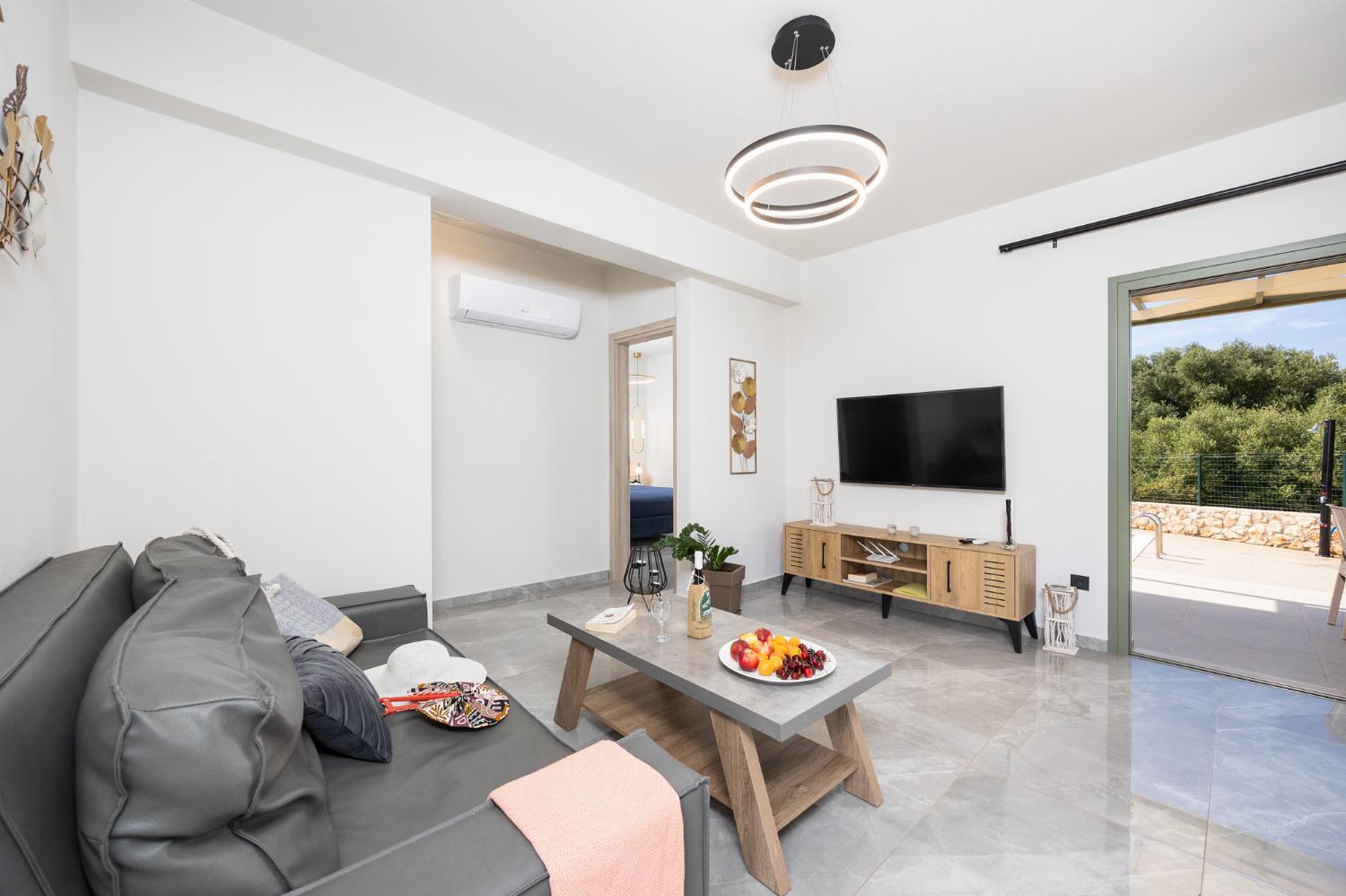 Open-plan living room with sofa, kitchen, A/C, WiFi internet, and satellite TV