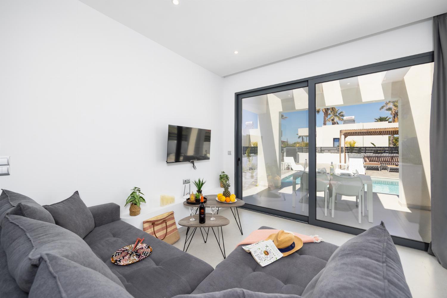 Open-plan living room with sofa, kitchen, A/C, WiFi internet, and satellite TV