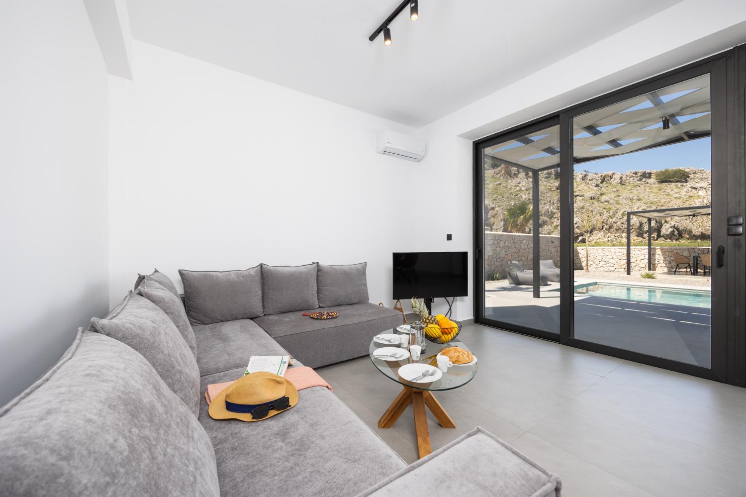 Open-plan living room with sofa, dining area, kitchen, A/C, WiFi internet, and satellite TV