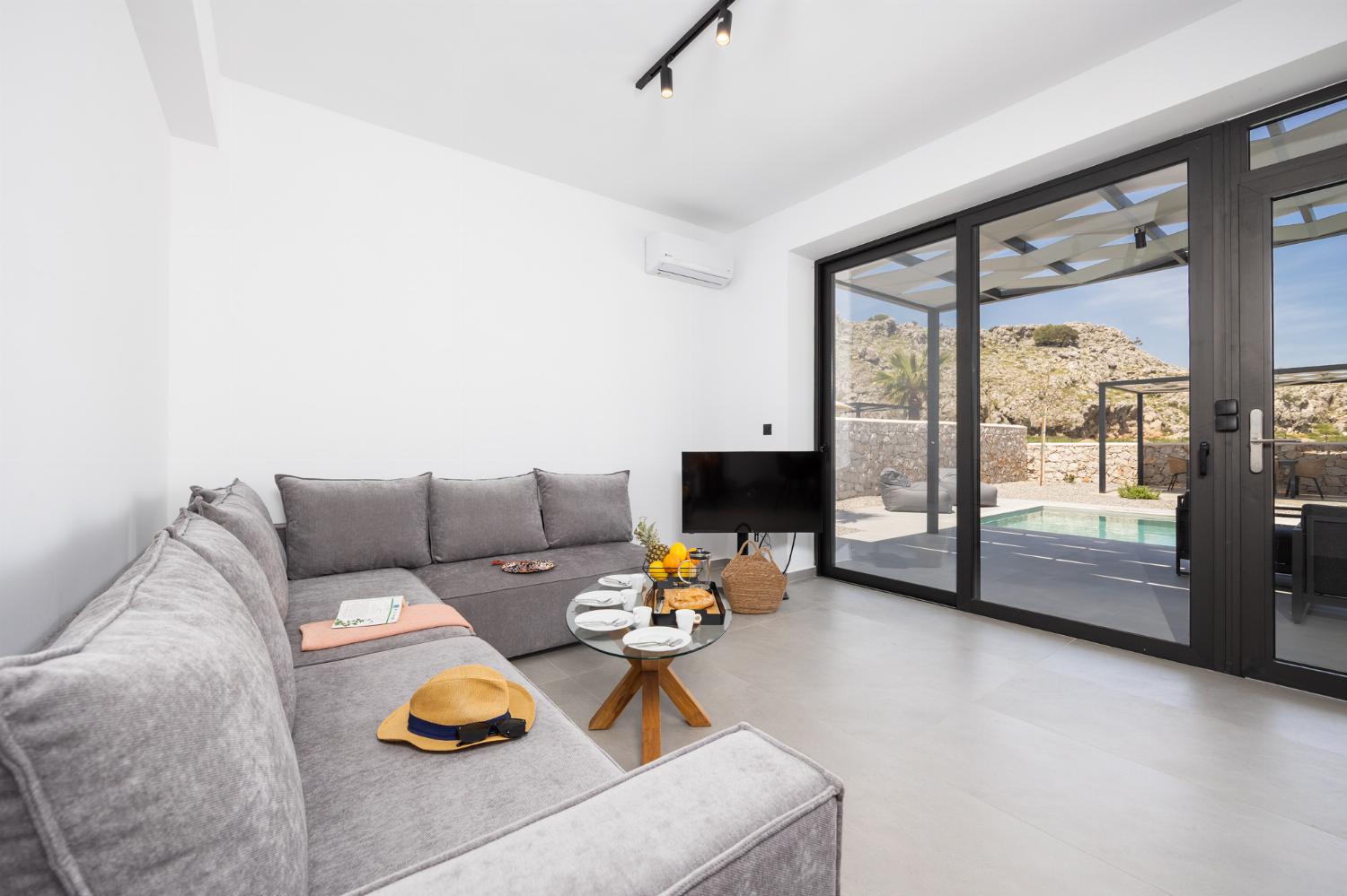 Open-plan living room with sofa, dining area, kitchen, A/C, WiFi internet, and satellite TV