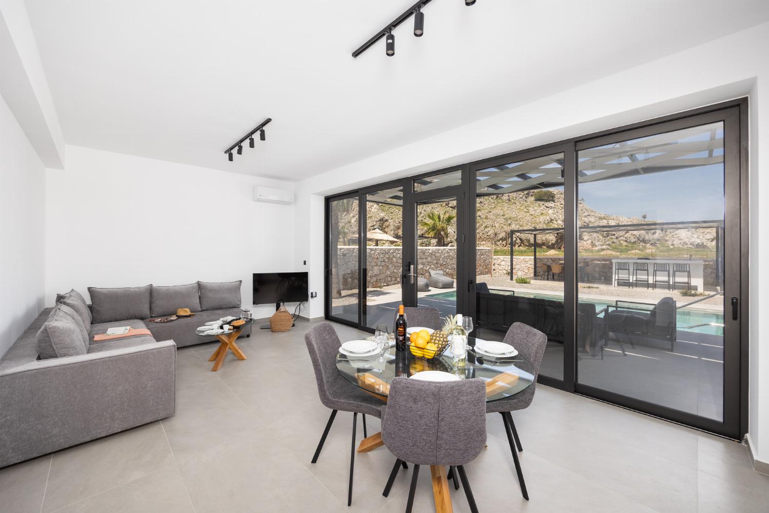 Open-plan living room with sofa, dining area, kitchen, A/C, WiFi internet, and satellite TV