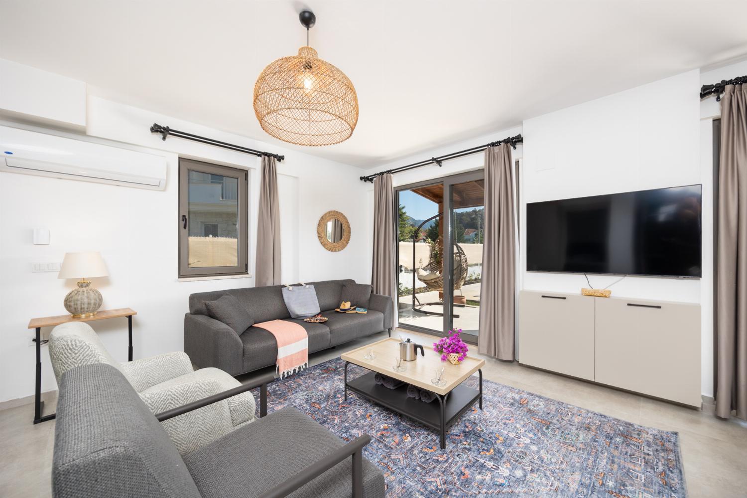 Open-plan living room with sofa, dining area, kitchen, A/C, WiFi internet, and satellite TV