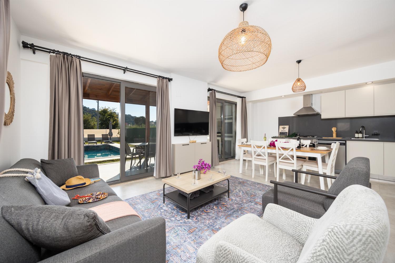 Open-plan living room with sofa, dining area, kitchen, A/C, WiFi internet, and satellite TV
