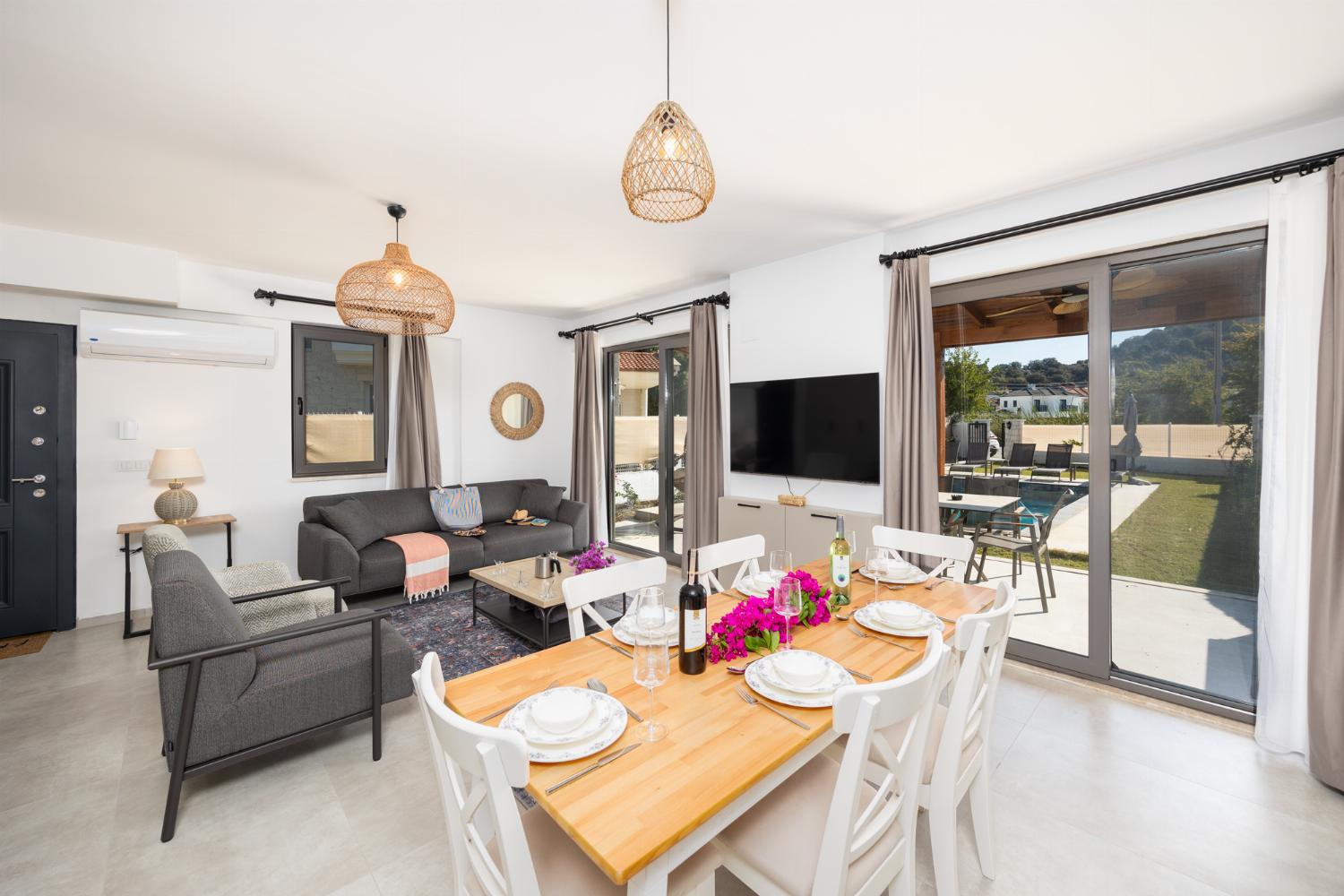 Open-plan living room with sofa, dining area, kitchen, A/C, WiFi internet, and satellite TV