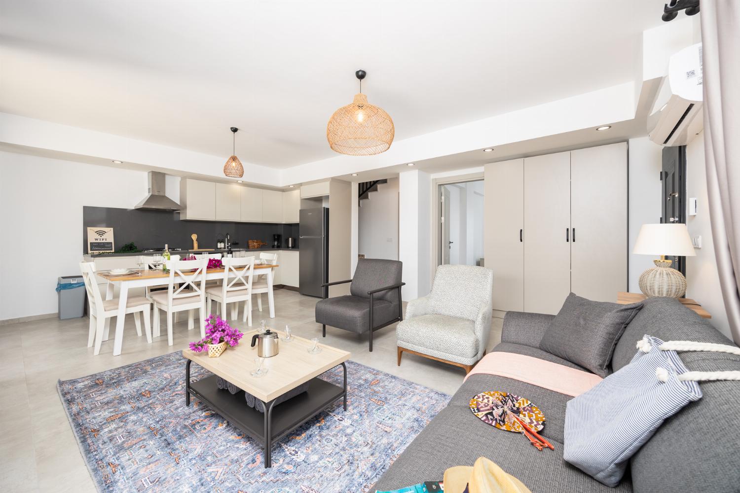 Open-plan living room with sofa, dining area, kitchen, A/C, WiFi internet, and satellite TV
