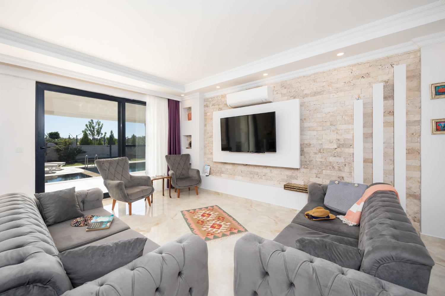 Main building: open-plan living room with sofas, dining area, kitchen, A/C, WiFi internet, and satellite TV