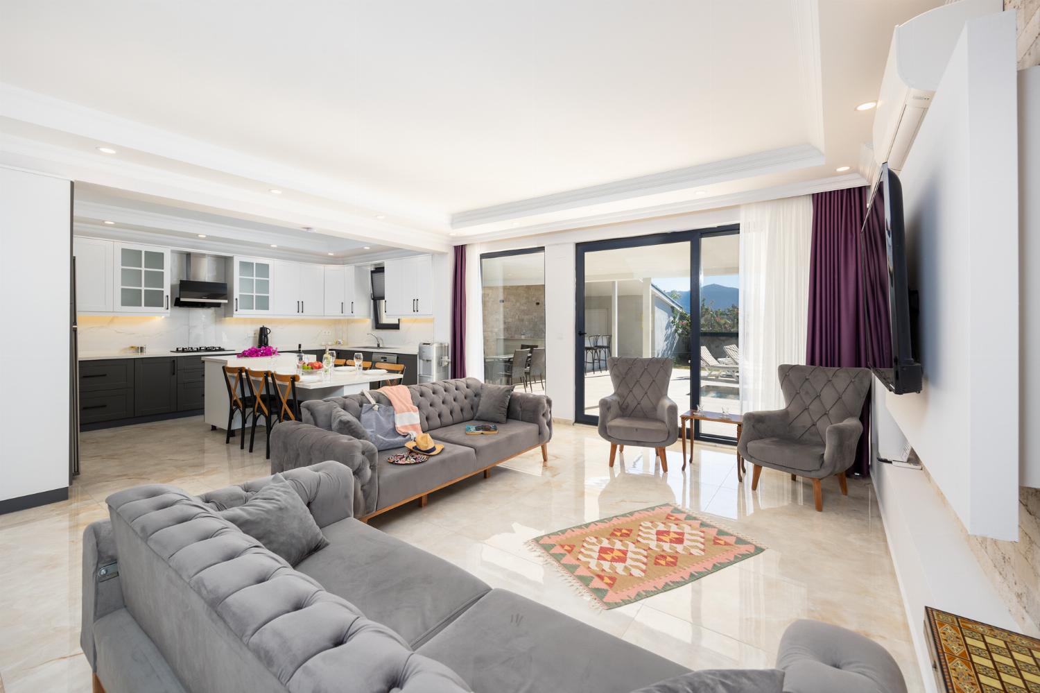 Main building: open-plan living room with sofas, dining area, kitchen, A/C, WiFi internet, and satellite TV