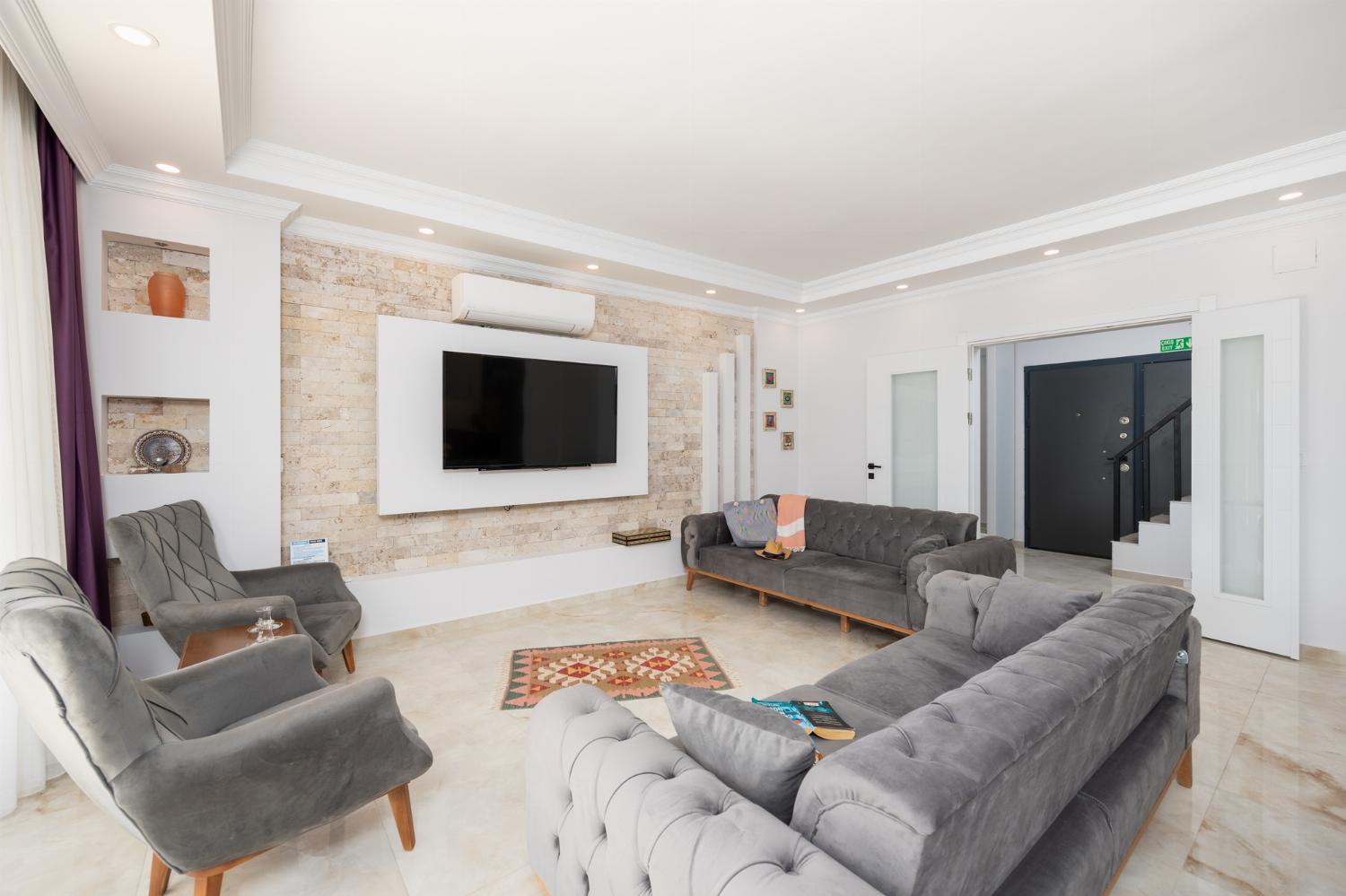Main building: open-plan living room with sofas, dining area, kitchen, A/C, WiFi internet, and satellite TV