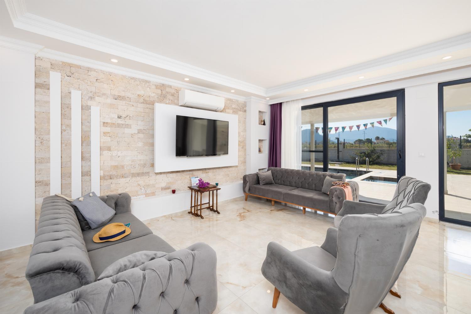 Main building: open-plan living room with sofas, dining area, kitchen, A/C, WiFi internet, and satellite TV