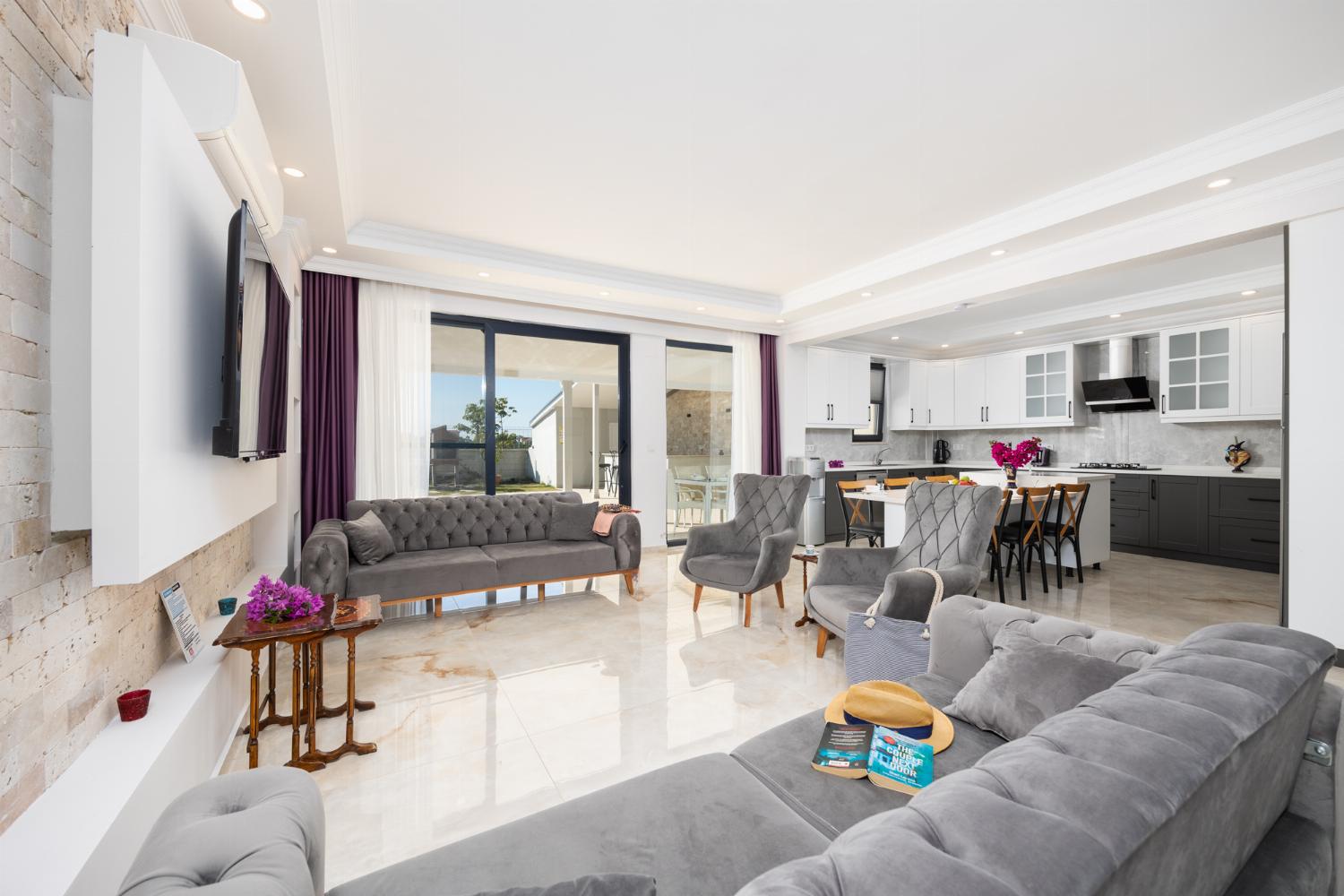 Main building: open-plan living room with sofas, dining area, kitchen, A/C, WiFi internet, and satellite TV
