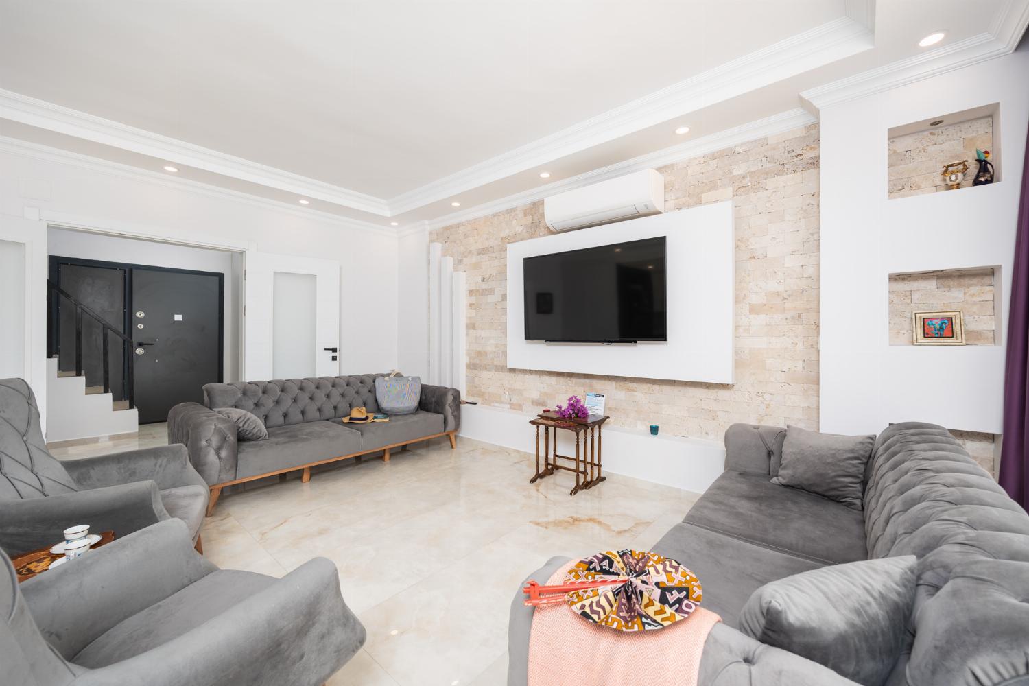 Main building: open-plan living room with sofas, dining area, kitchen, A/C, WiFi internet, and satellite TV