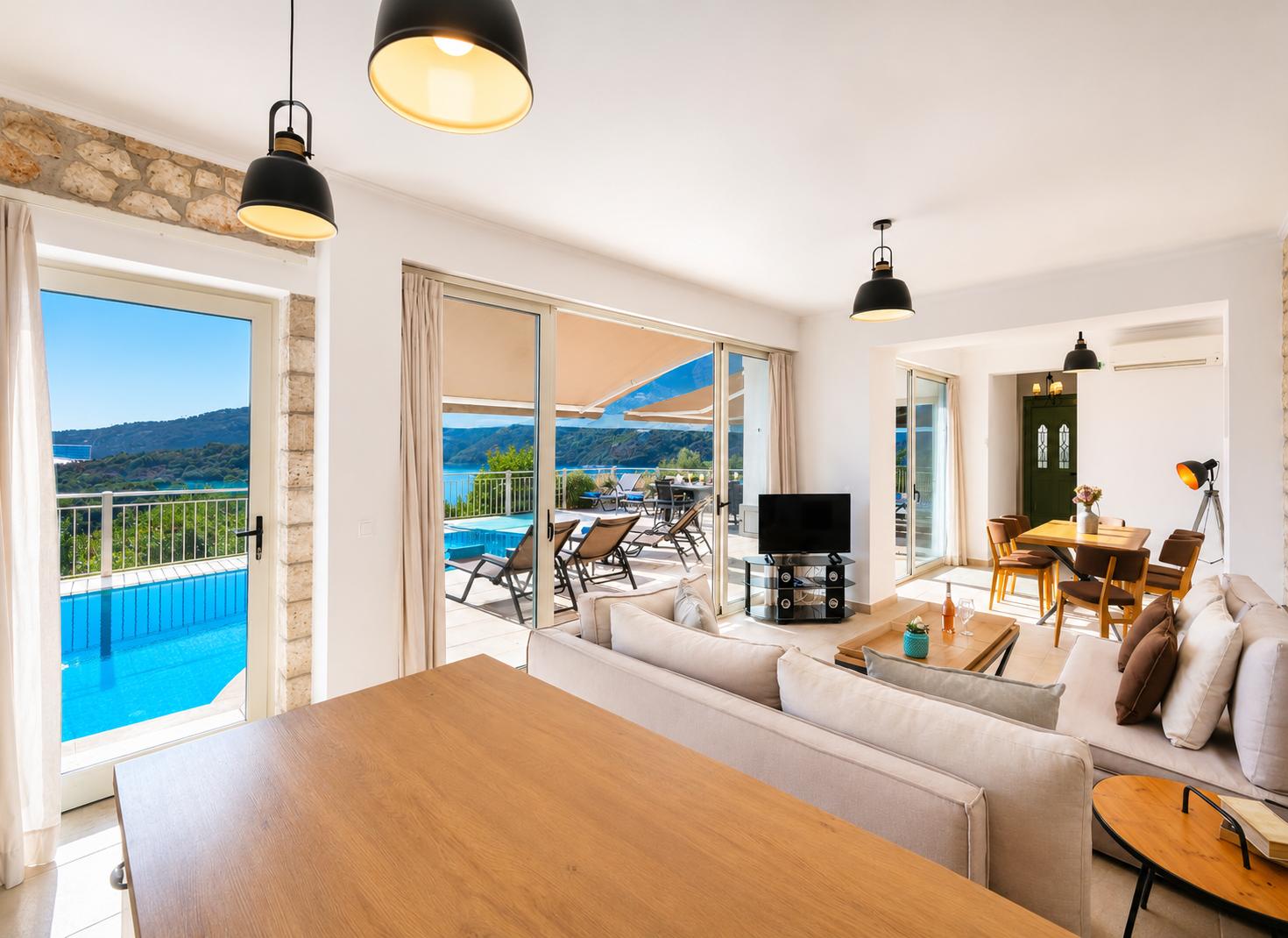 Open-plan living room with sofa, dining area, kitchen, A/C, WiFi internet, and satellite TV