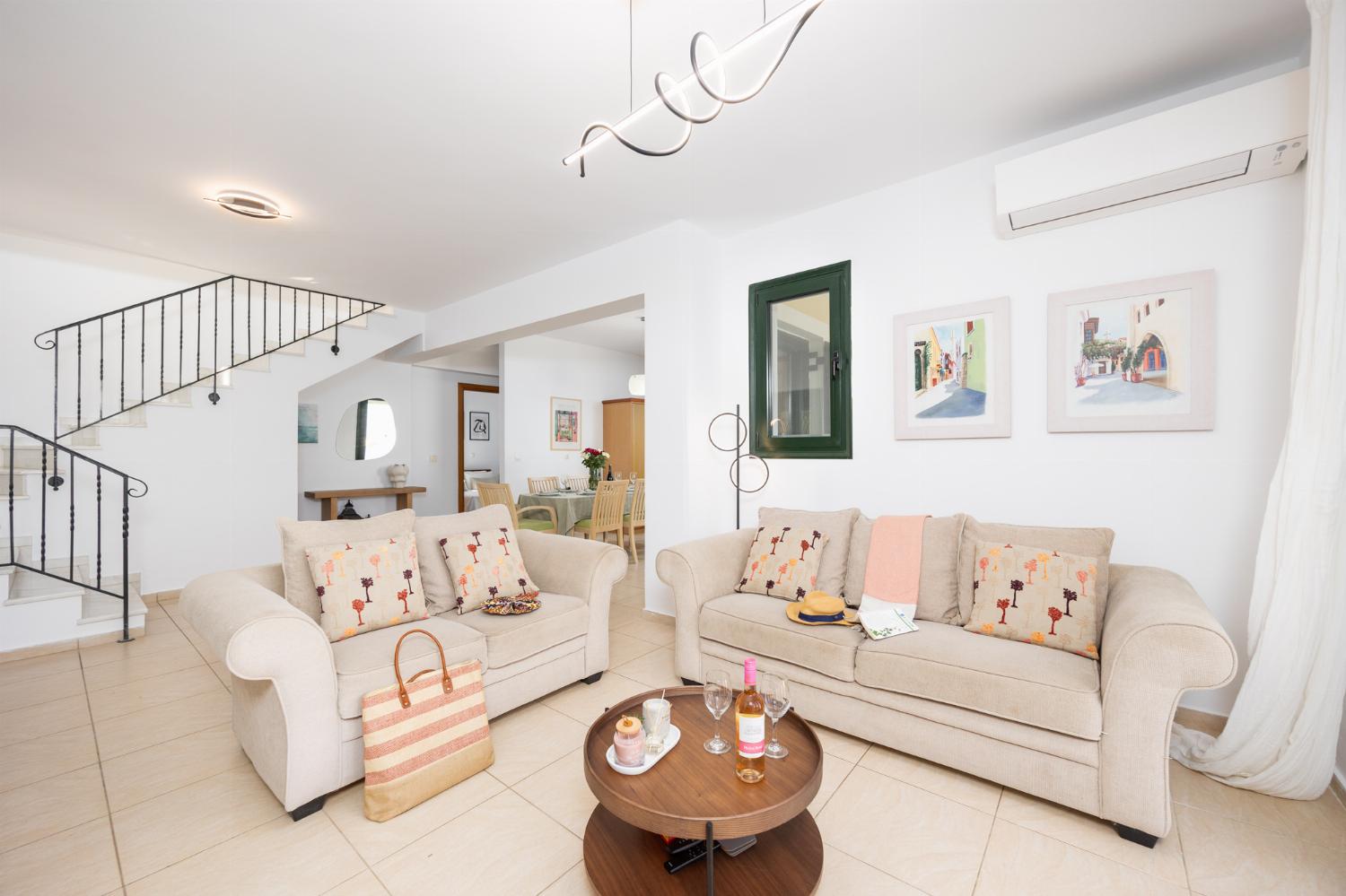 Open-plan living room with sofas, dining area, kitchen, ornamental fireplace, A/C, WiFi internet, satellite TV, and sea views