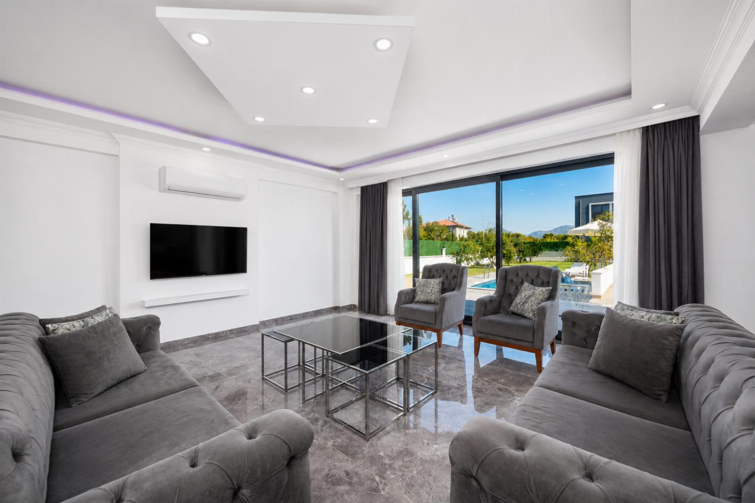 Open-plan living room with sofas, dining area, kitchen, A/C, WiFi internet, and satellite TV