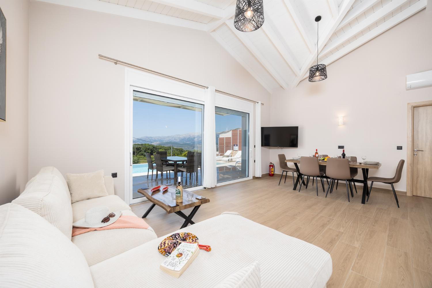 Open-plan living room with sofa, dining area, kitchen, A/C, WiFi internet, and satellite TV
