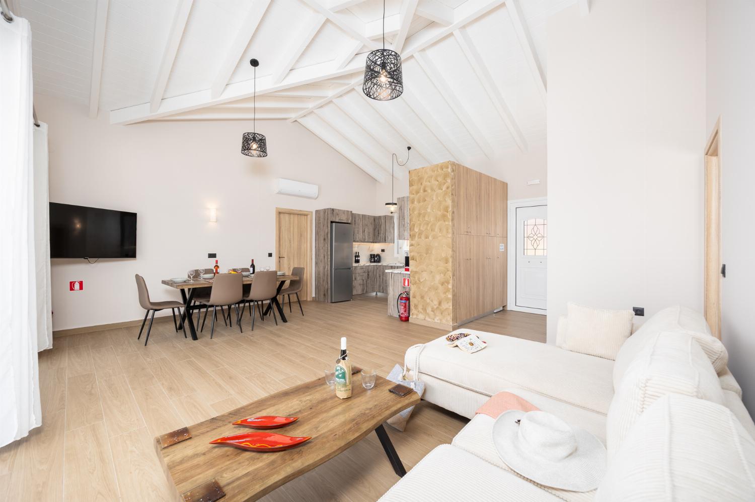 Open-plan living room with sofa, dining area, kitchen, A/C, WiFi internet, and satellite TV