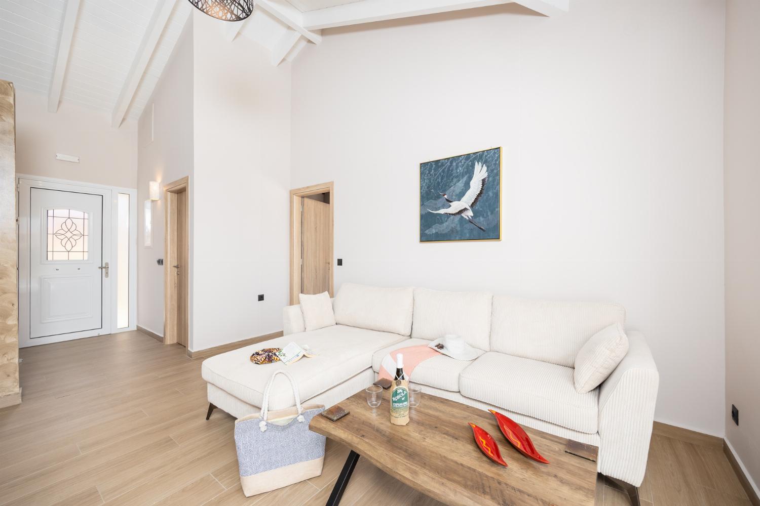 Open-plan living room with sofa, dining area, kitchen, A/C, WiFi internet, and satellite TV
