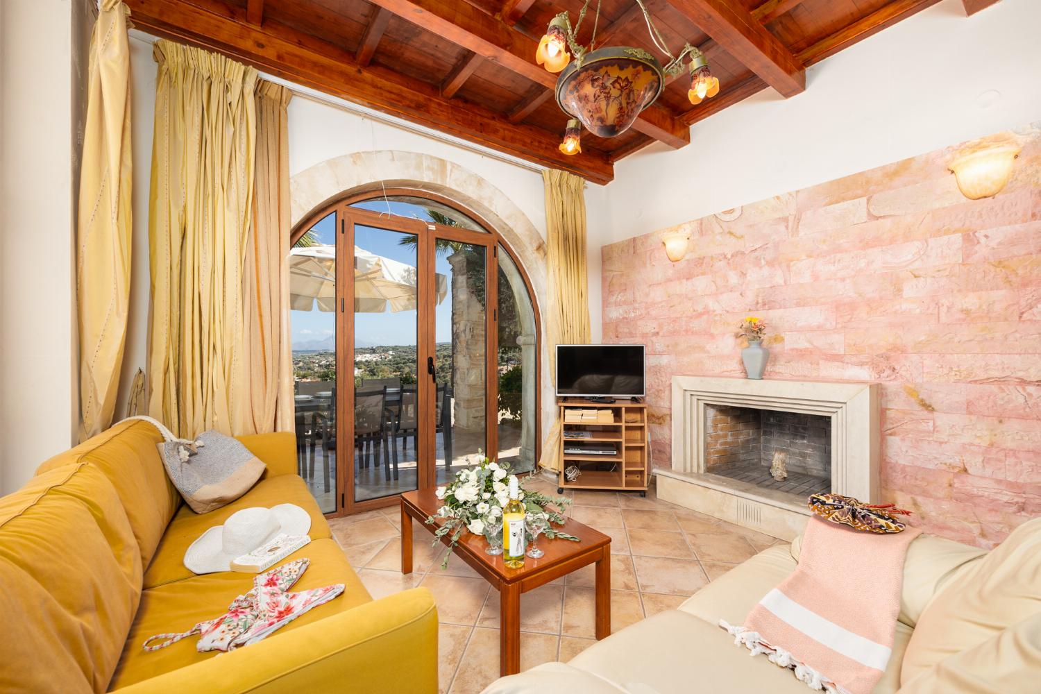 Open-plan living room with sofas, dining area, kitchen, ornamental fireplace, A/C, WiFi internet, and satellite TV