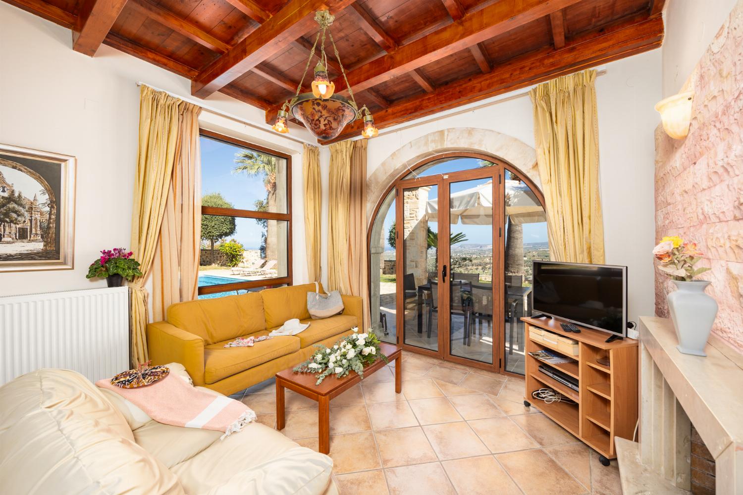 Open-plan living room with sofas, dining area, kitchen, ornamental fireplace, A/C, WiFi internet, and satellite TV