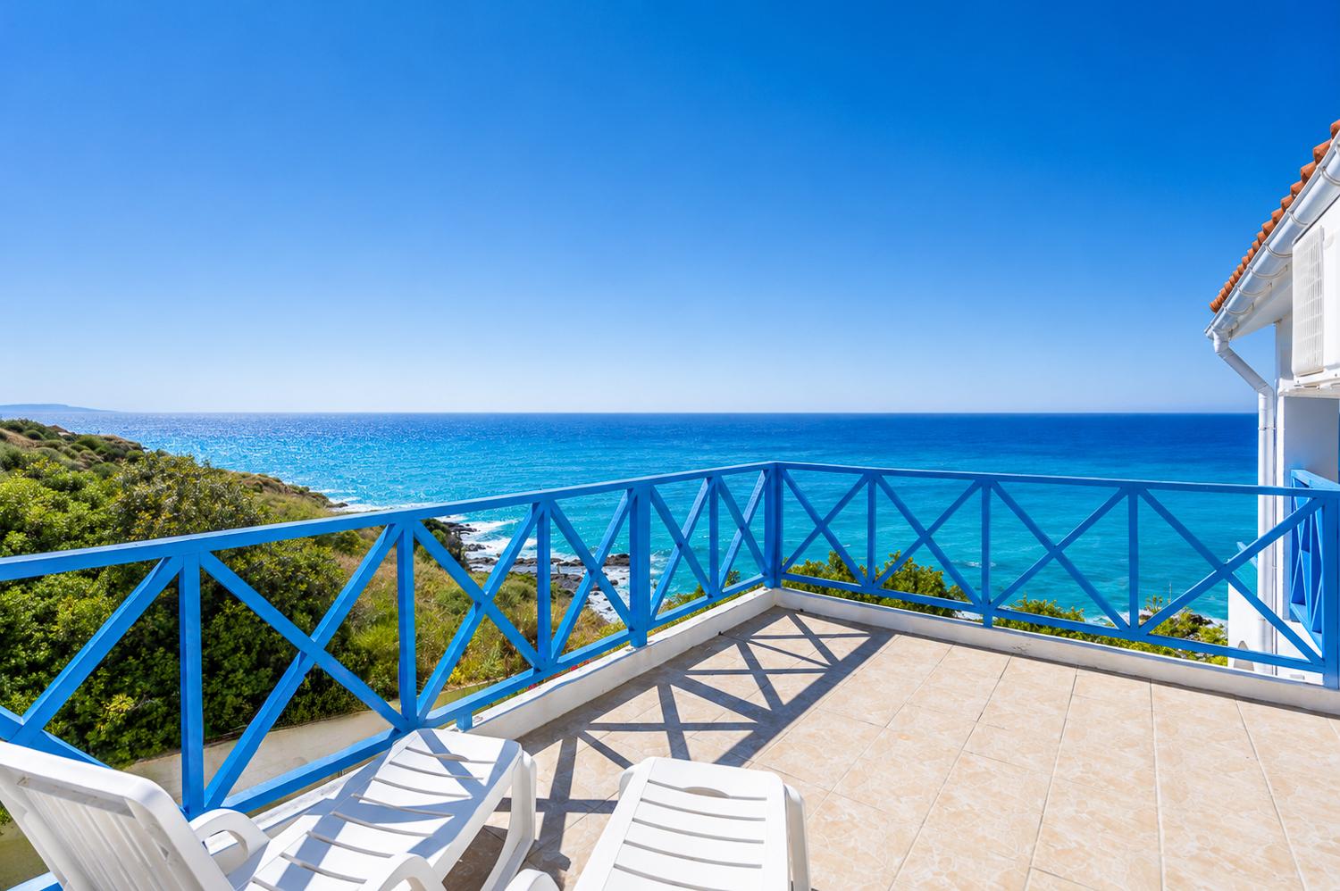Private balcony with sun loungers, bright blue railings, and breathtaking sea views.