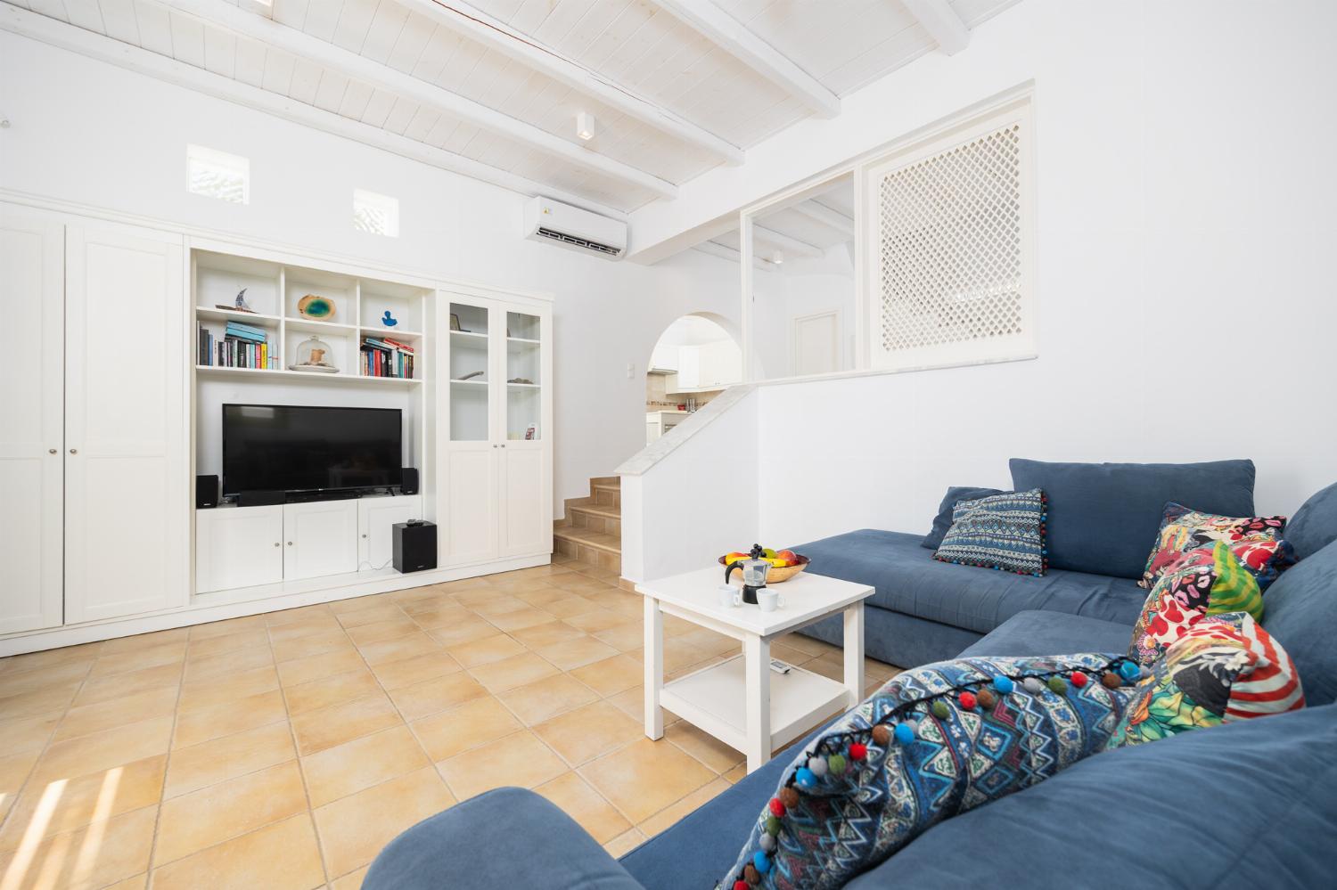 Open-plan living room with sofa, dining area, kitchen, A/C, WiFi internet, and satellite TV