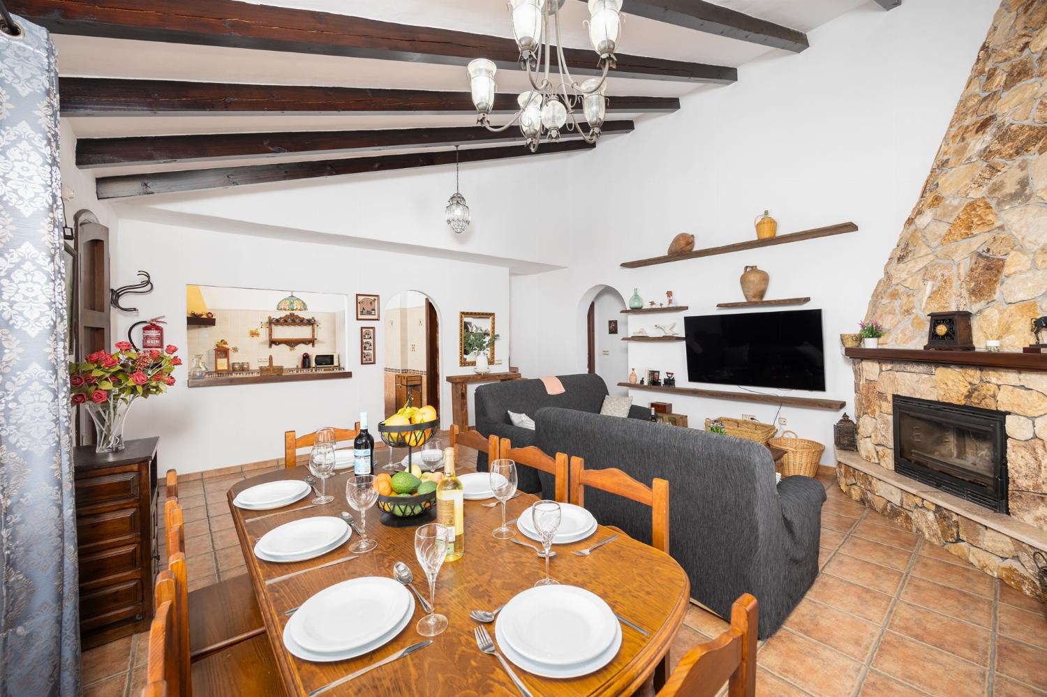 Open-plan living room with sofas, dining area, kitchen, ornamental fireplace, A/C, WiFi internet, and satellite TV