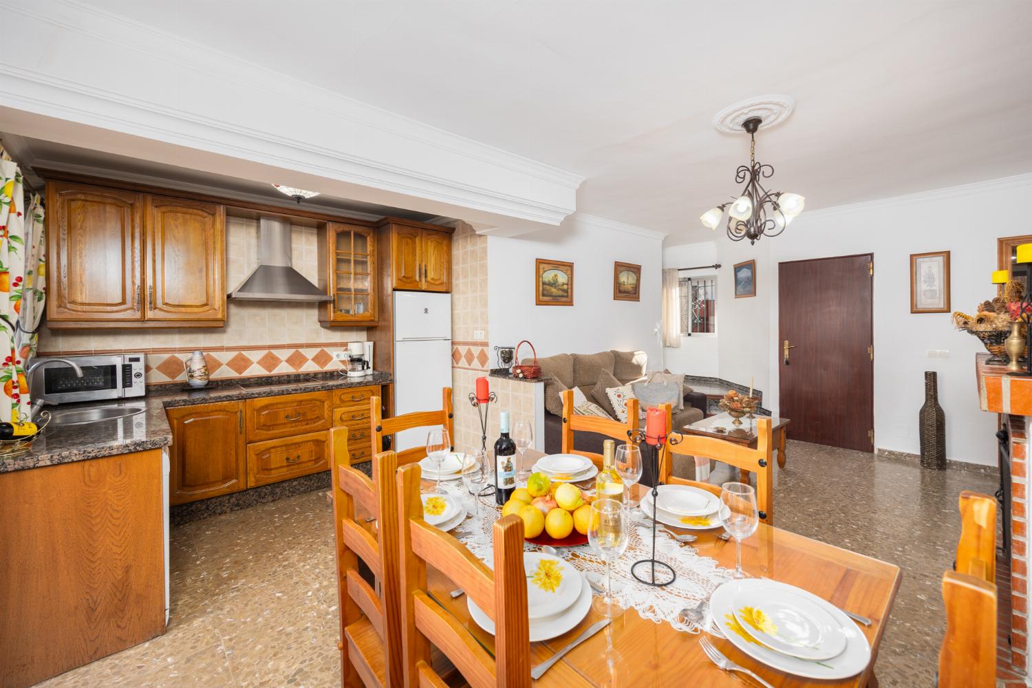 Open-plan living room with sofa, dining area, kitchen, ornamental fireplace, A/C, WiFi internet, and satellite TV