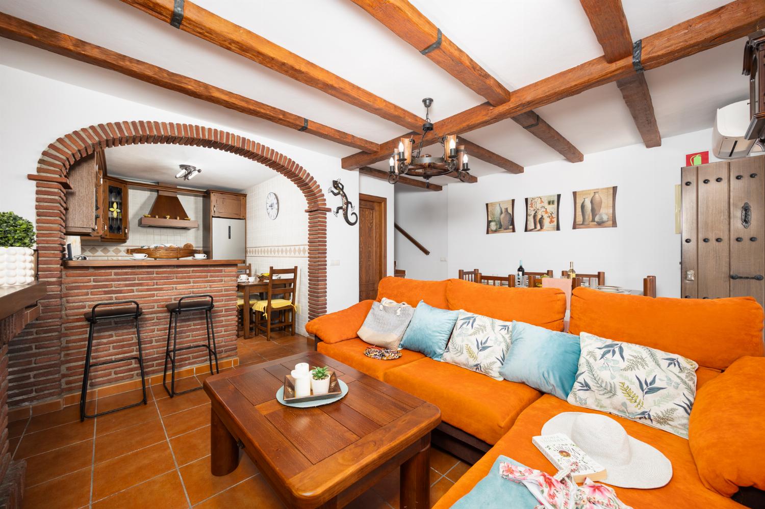 Open plan living room with sofa, dining area, kitchen, ornamental fireplace, A/C, WiFi internet, and satellite TV