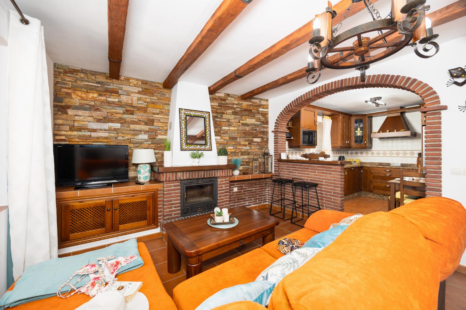 Open plan living room with sofa, dining area, kitchen, ornamental fireplace, A/C, WiFi internet, and satellite TV