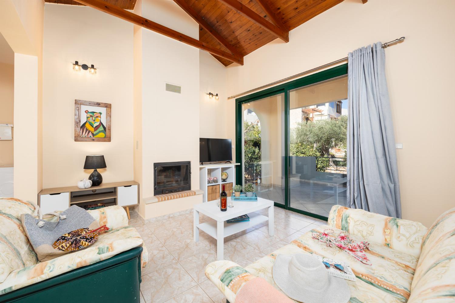 Open-plan living room with sofas, dining area, kitchen, ornamental fireplace, A/C, WiFi internet, and satellite TV