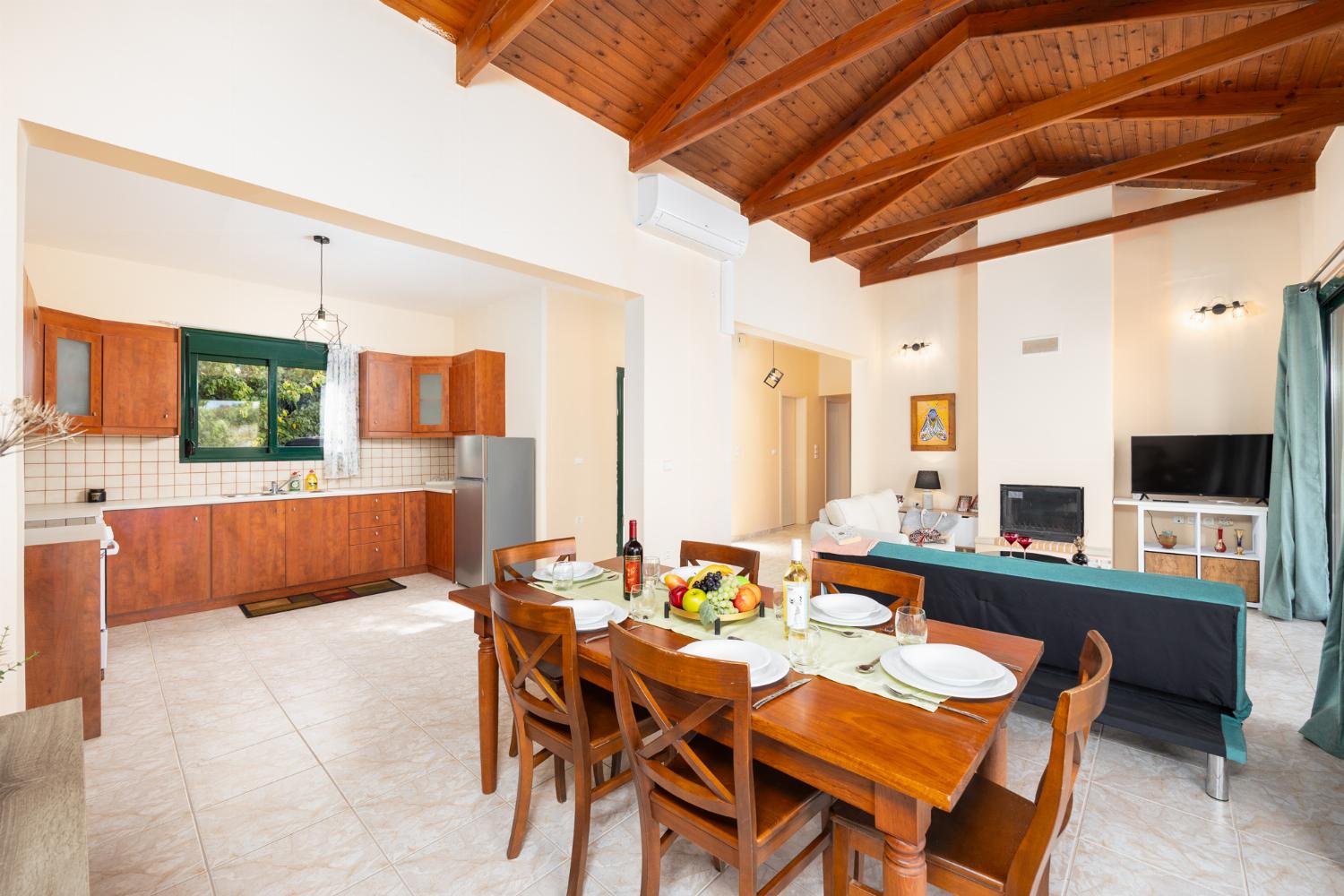 Open-plan living room with sofas, dining area, kitchen, ornamental fireplace, A/C, WiFi internet, and satellite TV