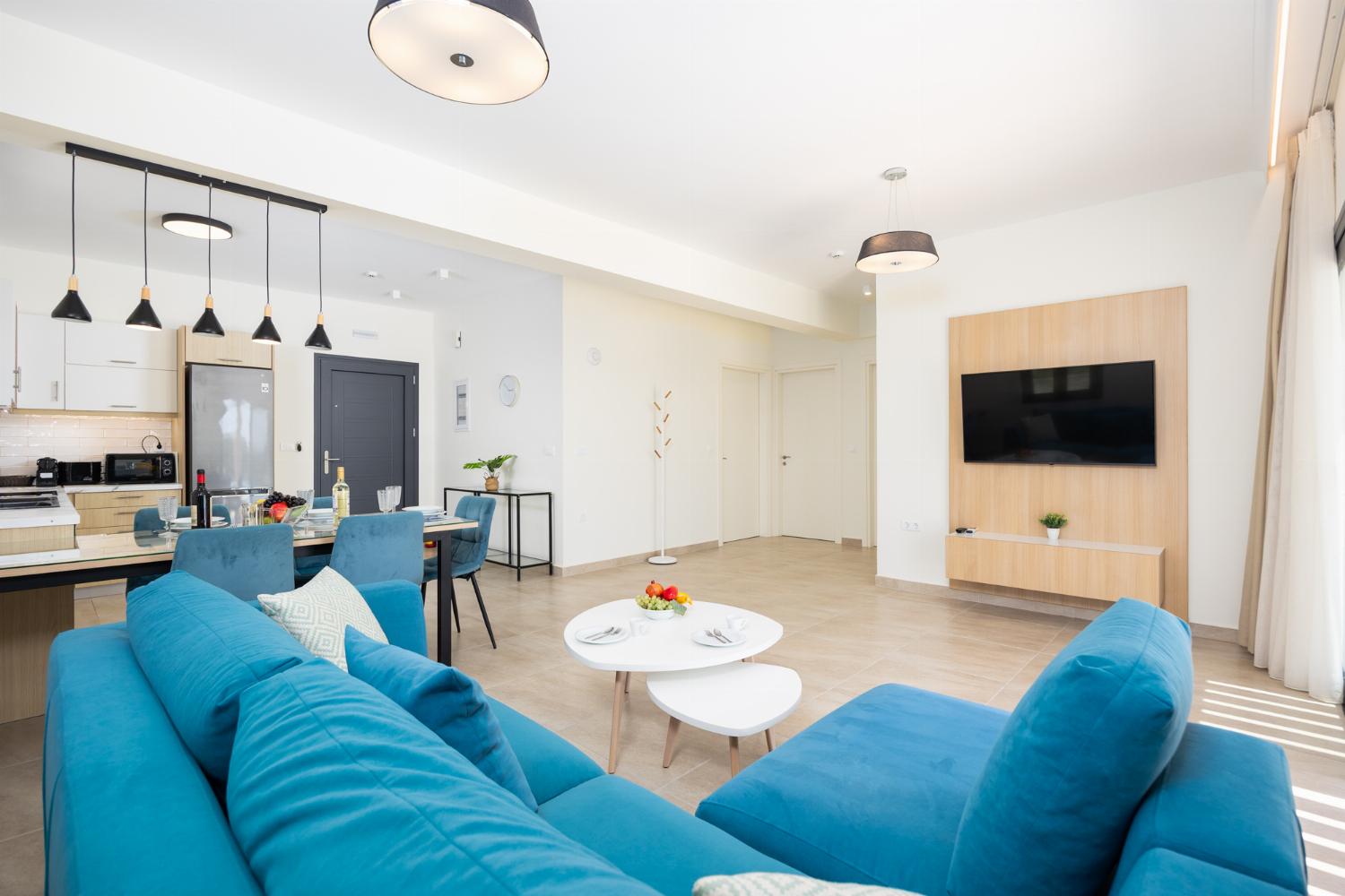 Open-plan living room with sofa, dining area, kitchen, A/C, WiFi internet, and satellite TV