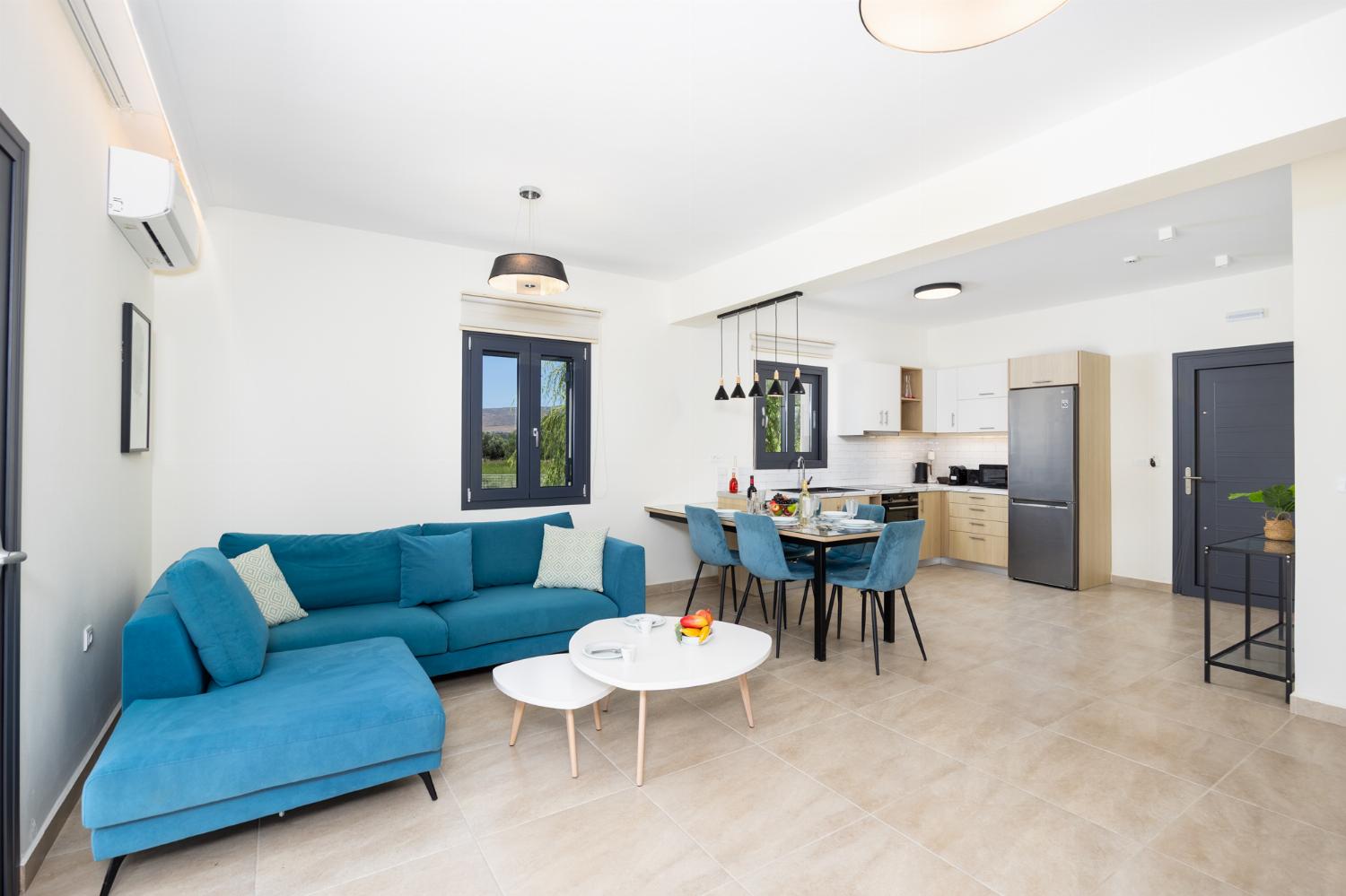 Open-plan living room with sofa, dining area, kitchen, A/C, WiFi internet, and satellite TV