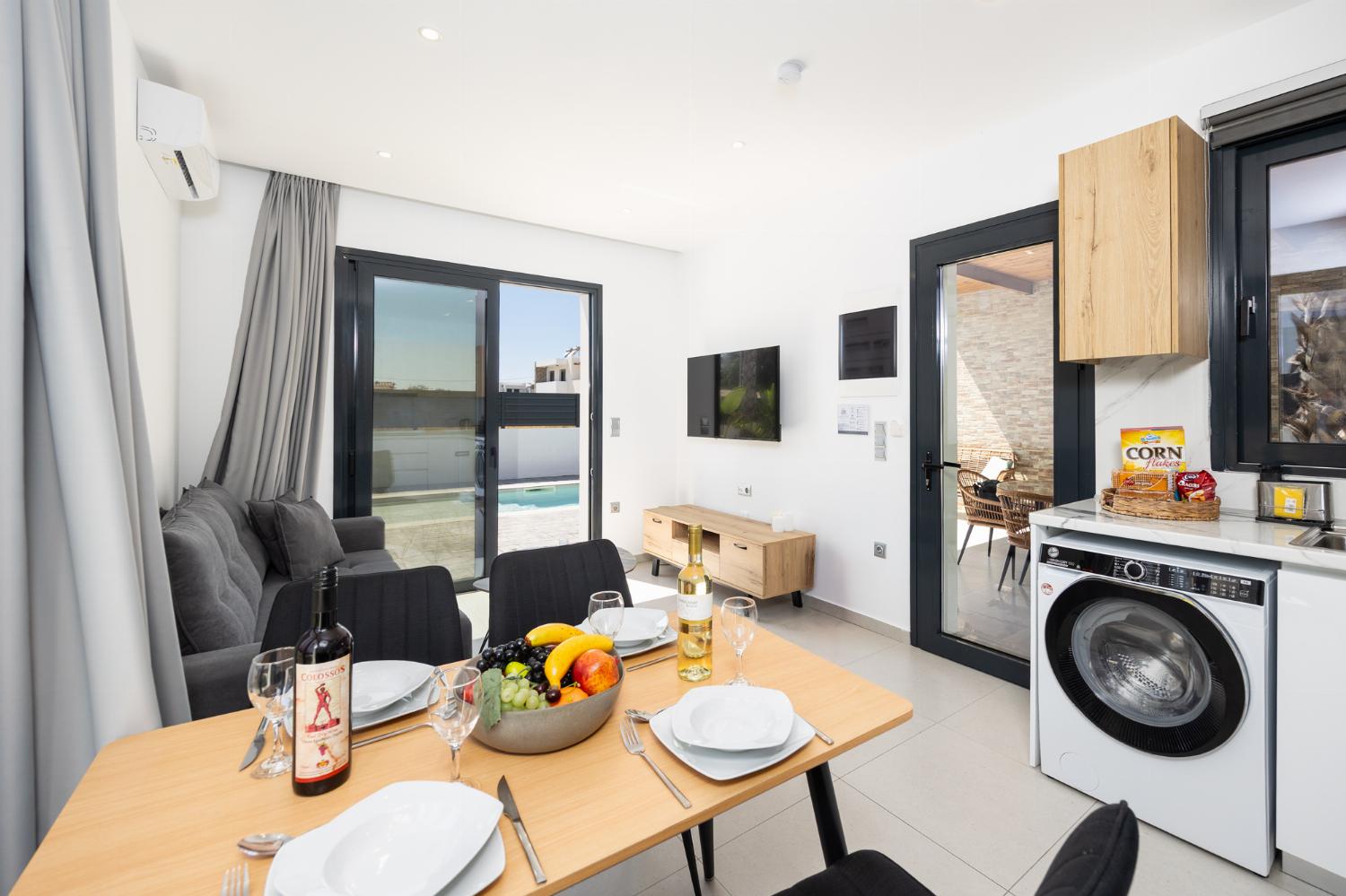 Open-plan living room with sofa, dining area, kitchen, A/C, WiFi internet, and satellite TV