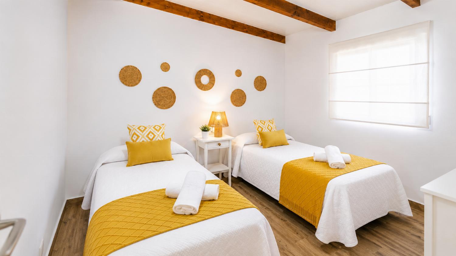 A bright twin bedroom with cheerful yellow accents and natural woven decor.