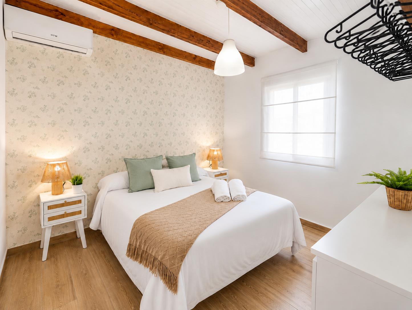 Cozy double bedroom with wooden beams, soft neutral decor, and warm natural touches.