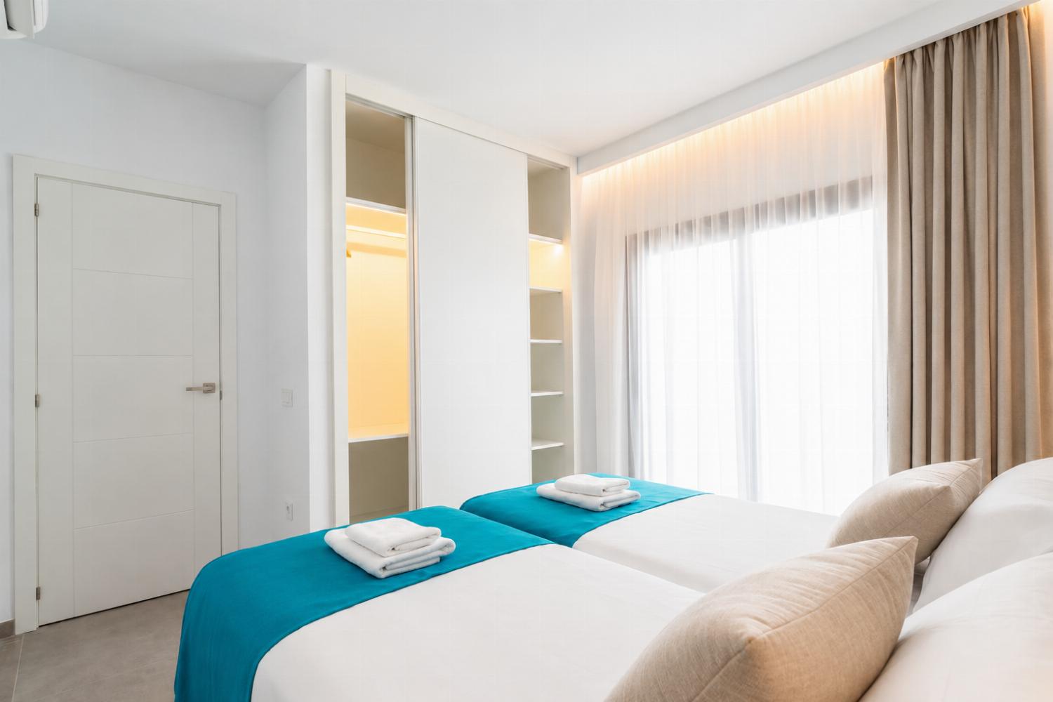Bright twin bedroom with clean modern decor and a spacious wardrobe.