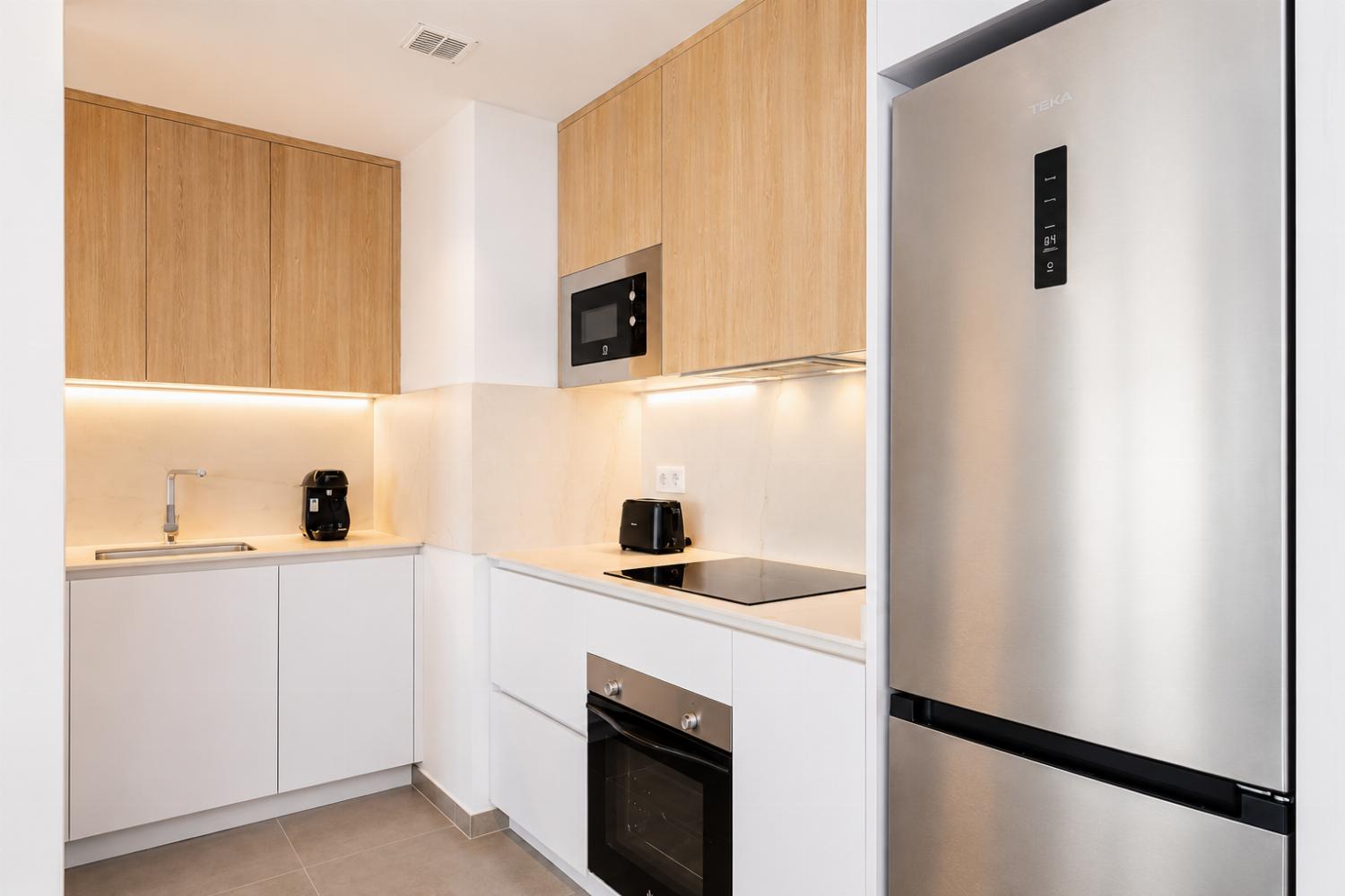 Modern open-plan kitchen and dining area with warm wooden cabinetry and a stylish table setting.