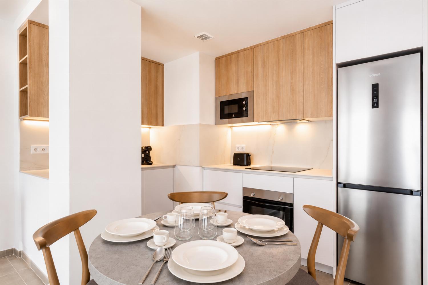 Modern open-plan kitchen and dining area with warm wooden cabinetry and a stylish table setting.