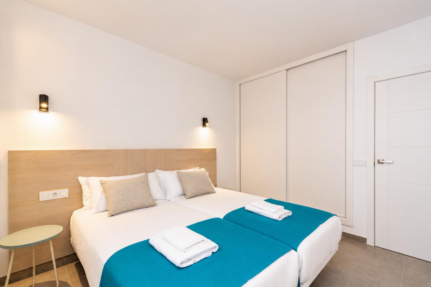 Bright twin bedroom with clean modern decor and a spacious wardrobe.