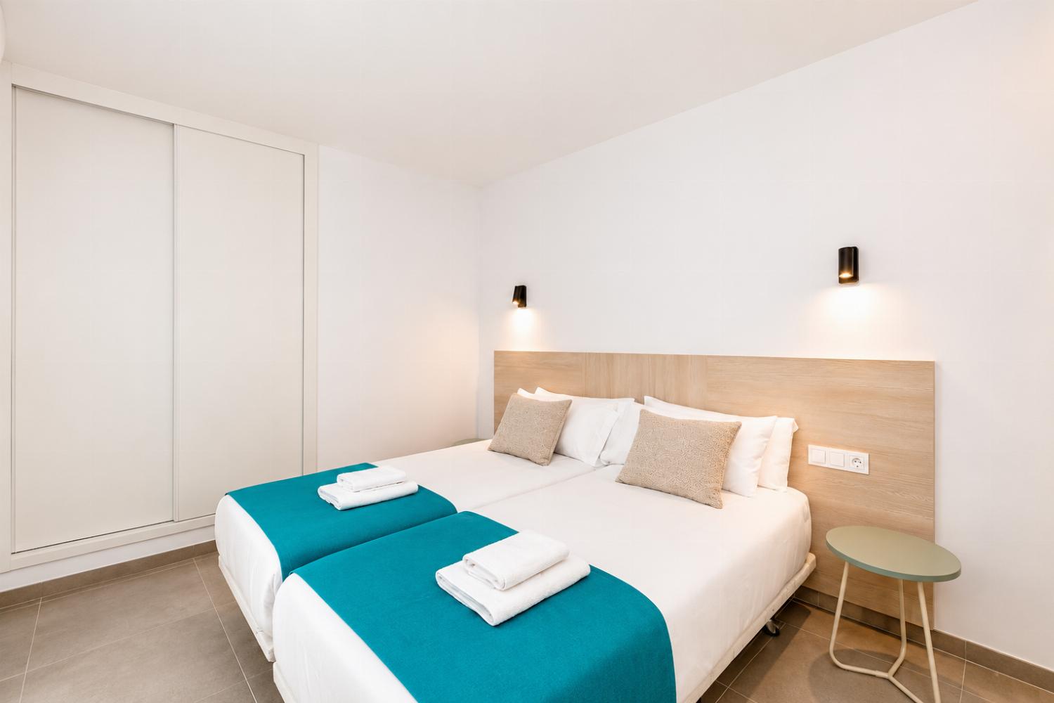 Bright twin bedroom with clean modern decor and a spacious wardrobe.